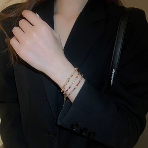 Close-up of a three-layer gold-plated bracelet with rainbow colorful gemstones on a model