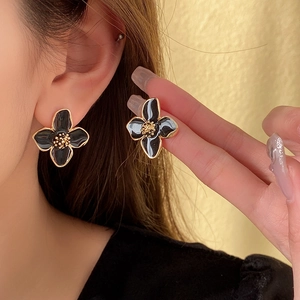 Gros plan de boucles d'oreilles fleurs noires aux bords dorés portées par un mannequin