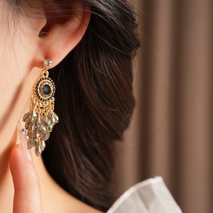 Close-up of bohemian chandelier earrings with blue stones and beaded tassels on a model
