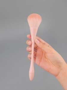 Close-up of fluffy pink gradient bristles and ergonomic handle on a makeup brush