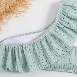 Macro detail of ruffled light green bikini fabric with textured polka dot pattern