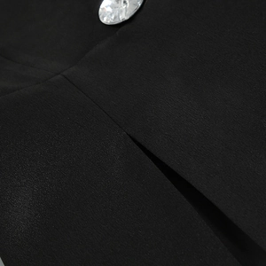 Detailaufnahme des schwarzen Sakko-Stoffs mit einem funkelnden Kristall-Strass-Knopf