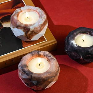 Detailed view of faceted geometric candle holders with marble textures and lit tea lights