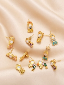 Detail of gold mermaid earrings with colorful zircon and opal on silk fabric