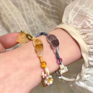 Détail macro d'un bracelet tissé main avec breloques chaton en résine et étoiles
