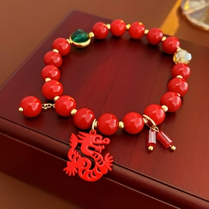 Détail d'un bracelet de perles rouges avec pendentif dragon sur boîte à bijoux vintage