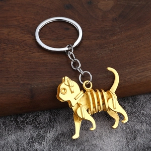 Mechanischer Katzen-Schlüsselanhänger in Goldoptik auf rustikalem Holzblock-Detail