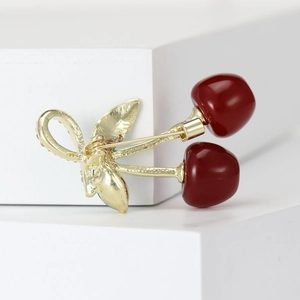 Charming gold cherry brooch with deep red fruits and sparkling diamond leaves on white background