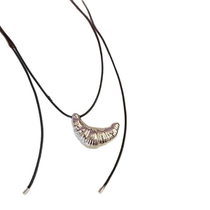 Minimalist silver croissant pendant necklace with black leather cord on white background
