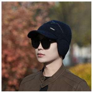Close-up of a navy blue knitted winter hat with earflaps and short brim on a model