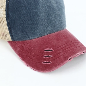 Detailed close-up of distressed vintage denim baseball cap with worn holes and mesh back