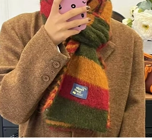 Detail of multi-color striped knit wool scarf featuring a blue FORME STUDIO woven label