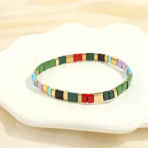 Detail of colorful enamel Tila bead bracelet with golden spacers on a white tray