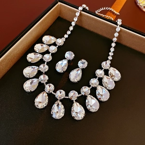 Détail d'un ensemble de collier et boucles d'oreilles goutte d'eau dans un écrin noir