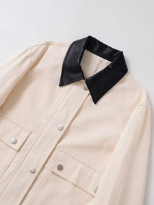 Détail de la veste cargo avec col en cuir noir et boutons métalliques sur toile crème