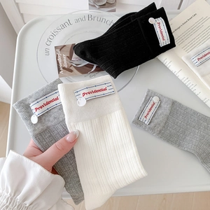 Three pairs of stylish ribbed mid-calf socks in black white and grey with cloth labels