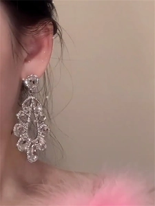 Close-up of elegant silver drop earrings with crystals worn by a model in warm light