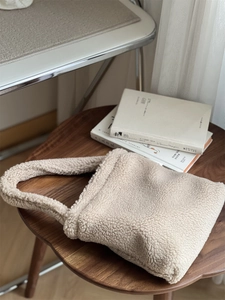 Close-up of cream teddy fleece handbag showing soft faux fur texture and handle