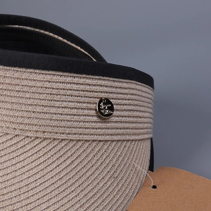 Minimalist straw sun visor hat with black ribbon edge and golden metal badge detail
