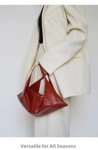 Model showing a reddish-brown leather croissant bag with unique folded pleats and soft texture