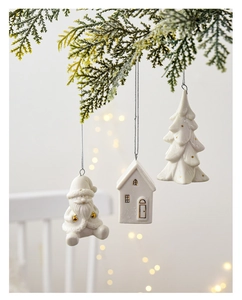 White ceramic Christmas ornaments hanging on pine branch with gold details