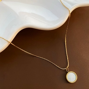 18K gold plated titanium necklace with round white shell pendant on elegant ceramic plate