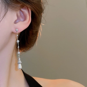 Macro shot of long silver tassel earrings with zircon flowers and drop pearl pendants