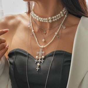 Close-up of layered faux pearl necklace with sparkling rhinestone cross pendant on model