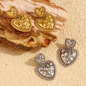Détail de boucles d'oreilles cœur vintage avec texture météorite martelée en or et argent