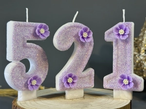 Detailed view of handmade purple glitter number candles 5 2 1 with small floral accents