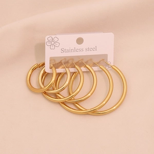 Three pairs of polished golden stainless steel hoop earrings in different sizes on a card