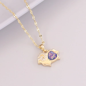 Macro detail of 18K gold necklace pendant with blue glitter inlay and sparkling crystals