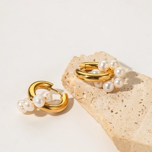 Golden stainless steel hoop earrings with natural freshwater pearls on a stone