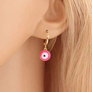 Close-up of a gold hoop earring featuring a pink enamel evil eye pendant on a model