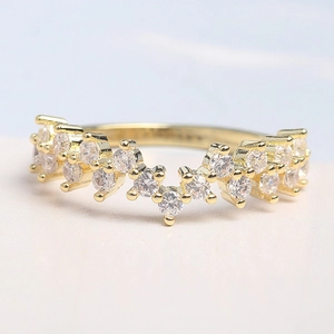 Macro detail of wave-shaped gold ring with pavé-set cubic zirconia and jagged texture