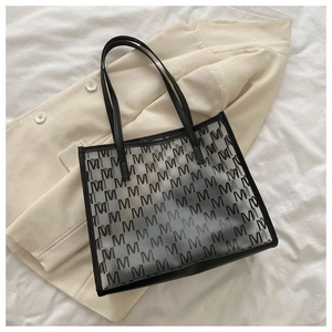 Close-up of black transparent tote bag with M-letter print on beige blazer background