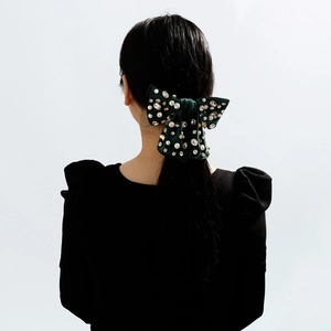 Fermaglio per capelli in velluto verde scuro con perle e strass su una modella