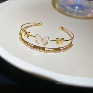 Close-up of double-layer gold bracelet with shell butterfly and sparkling zircon details