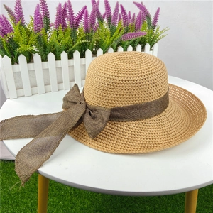 Detailed close-up of straw sun hat with dark brown bow ribbon against garden background