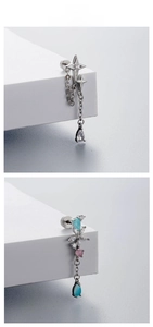 Detail of silver drop earrings with blue gemstones and star charms on stone props