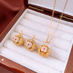 Detail of vintage hollow ball jewelry set with red ruby and zircons in wooden box
