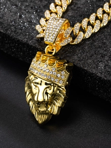 Macro shot of gold lion head pendant with crystal crown and iced out cuban chain