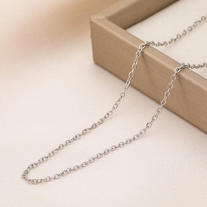Collier classique en chaîne croisée en acier inoxydable argenté dans un écrin beige