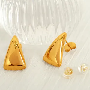 Polished gold triangle titanium steel stud earrings set on white textured fabric