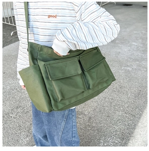 Close-up of army green canvas messenger bag with large front flap pockets on a model