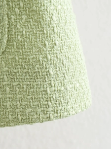 Detailopname van mintgroene tweed stoftextuur en fijn geweven details van de jas