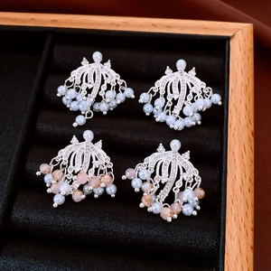 Detailed shot of silver tassel earrings with pearls and crystals on black velvet