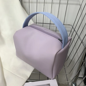 Chic lavender square handbag with textured blue handle on a modern metal display