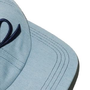 Macro detail of navy blue embroidery on light blue denim baseball cap with reinforced stitching