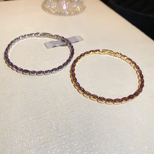 Close-up of gold and silver tennis bracelets with purple oval-cut gemstones and claw setting
